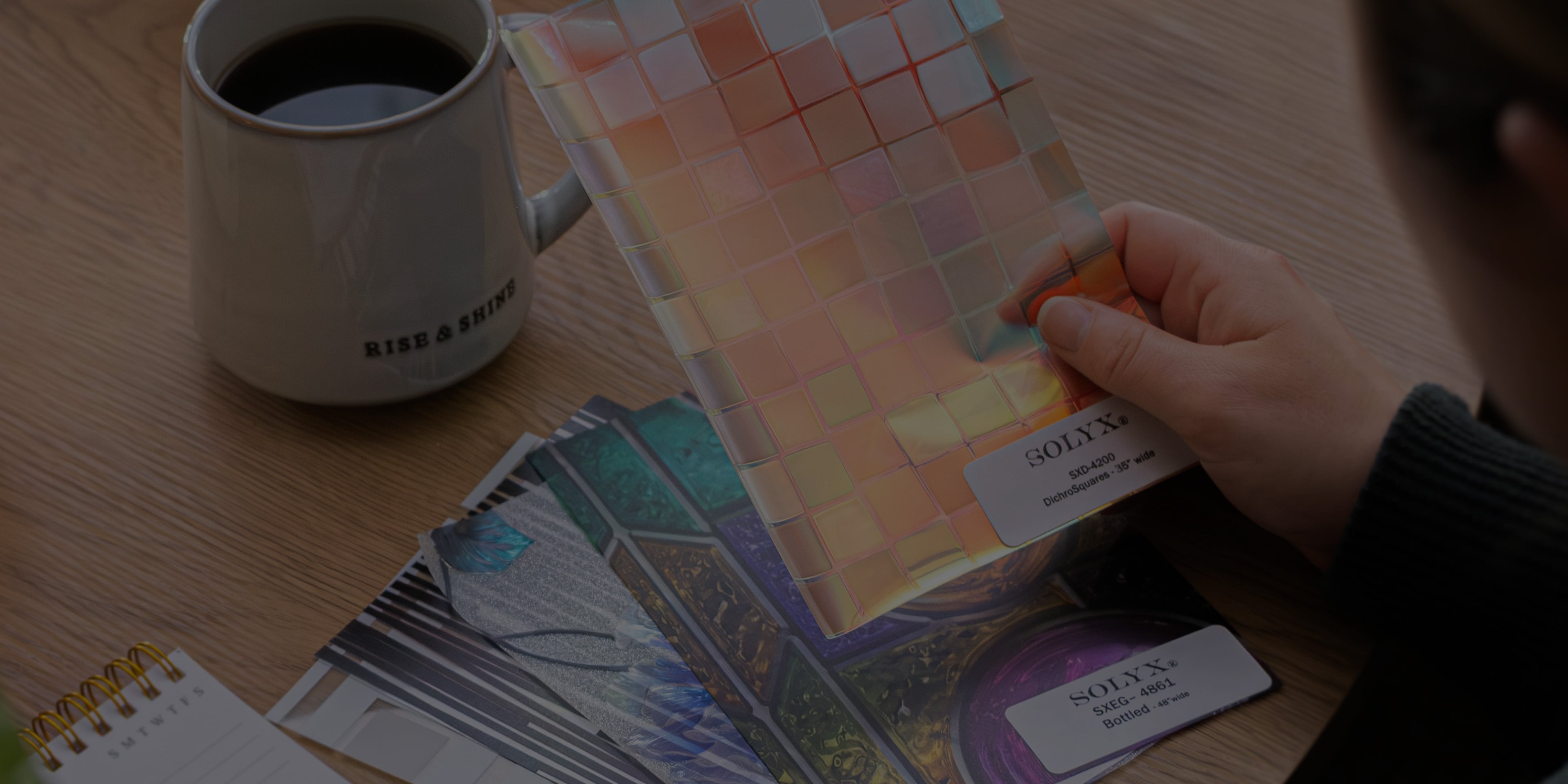 Decorative film samples laid out on a tabletop beside a cup of coffee